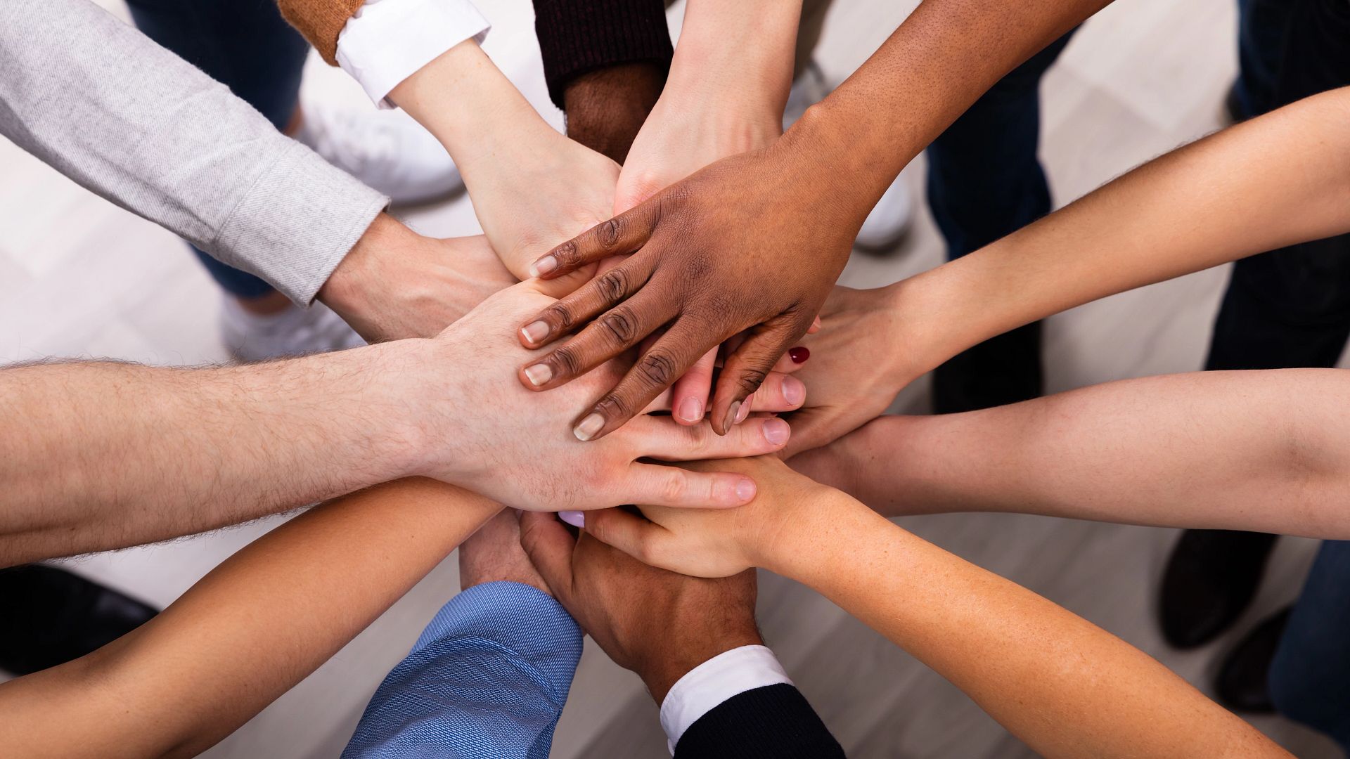 Overhead view of arms of varied skin tones in a circle with hands in the center