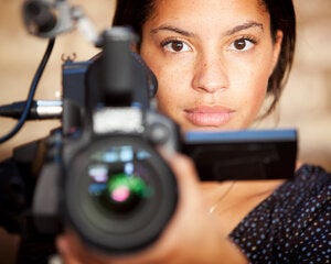 A confident glance from a video camera operator engaging eye contact with her subject during filming.
