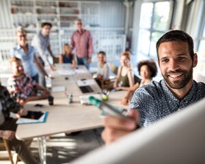 Person writing on the whiteboard in a meeting