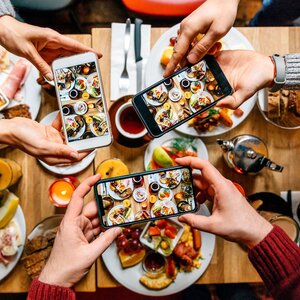 phones taking photos of food above a table