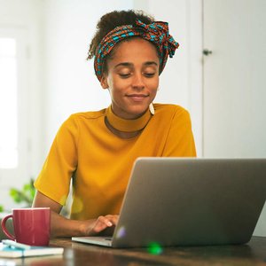 black woman in yellow sweater at laptop