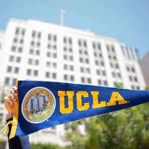 UCLA's downtown Los Angeles Trust building, with hands holding a pennant in foreground