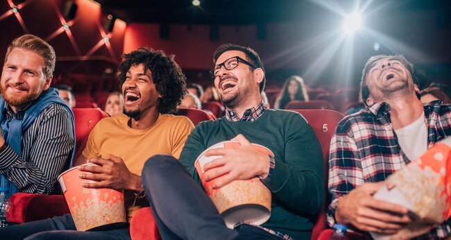 movie goers laughing with buckets of popcorn