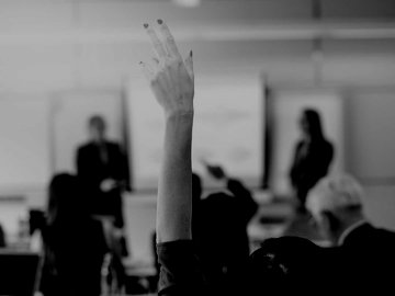 Businesswoman raising hand in professional classroom.