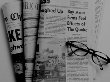 Reading glasses resting on top of newspapers.