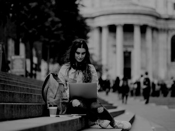 Woman in UK typing on laptop while sitting on steps.