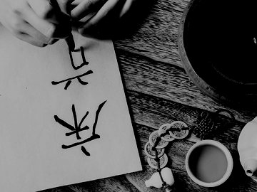 asian woman practicing calligraphy with ceramic teapot and teacup on the side