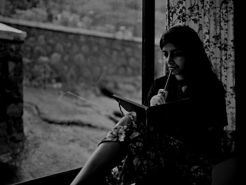 Woman writing in a diary sitting at the window