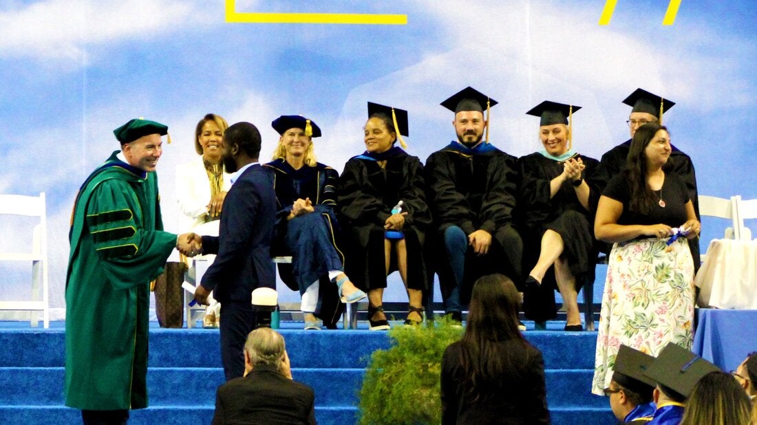 Graduate shakes Dean's hand at UCLA Extension Graduation Ceremony.