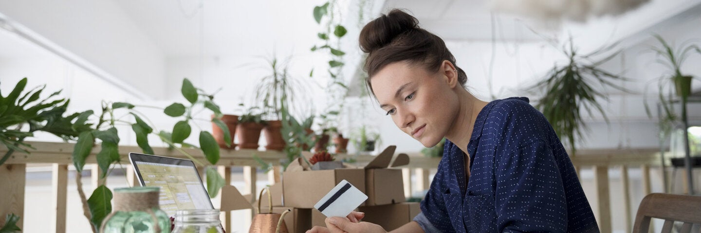 Female small business owner looking over finances and holding a credit card.