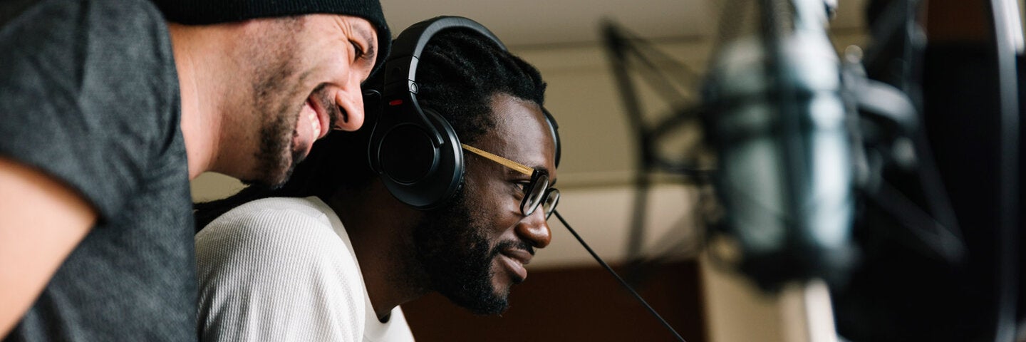 one man with headphones another man smiling supervising 