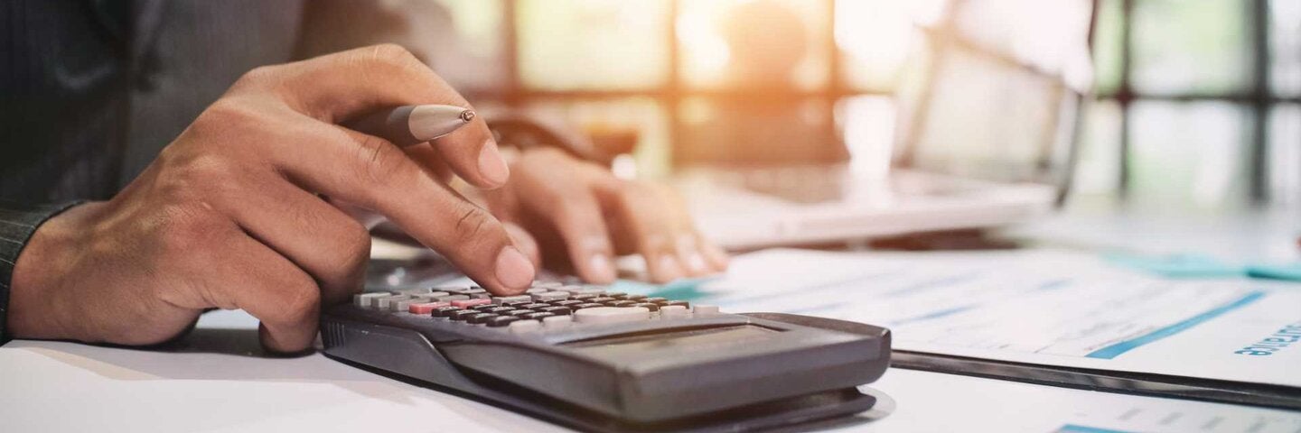 Businessman checking financials on a calculator.