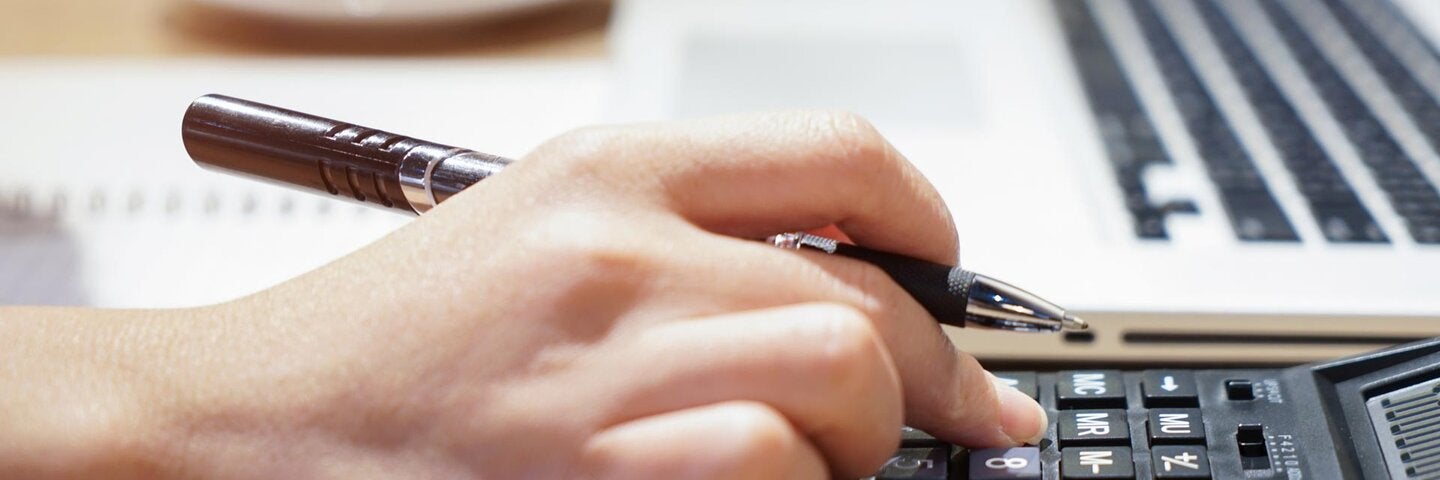 hand holding pen using calculator