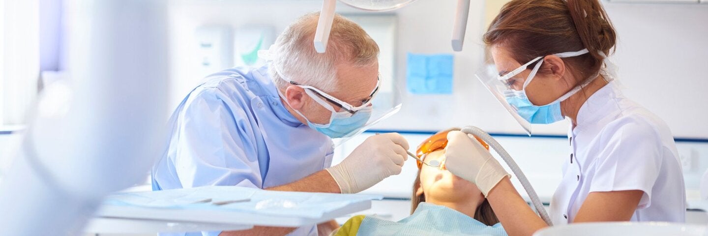Dentist and assistant examining patient's teeth.