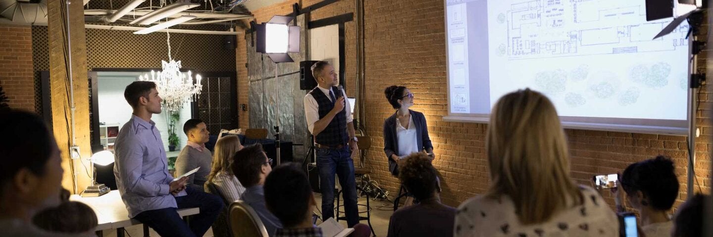 Employees viewing plans on projection screen in conference room