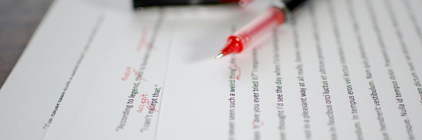 Red pen editing a manuscript