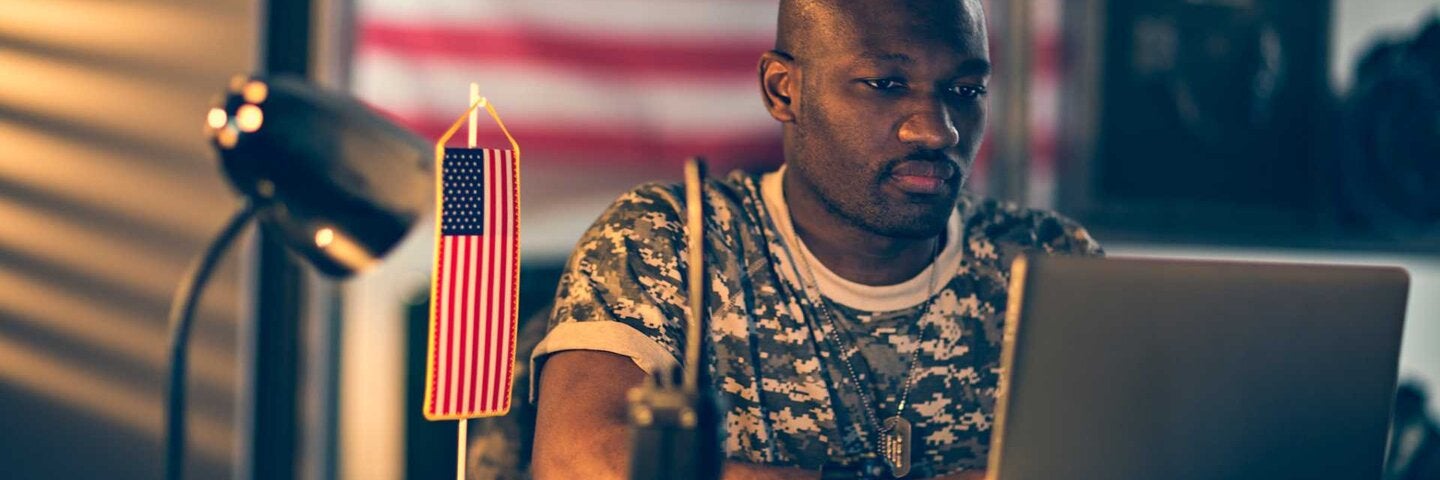 An american soldier using laptop in home office