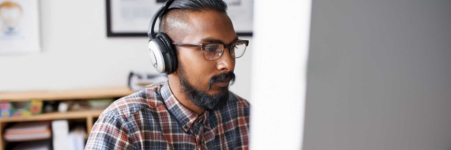 A young businessman listening to music while working on his computer