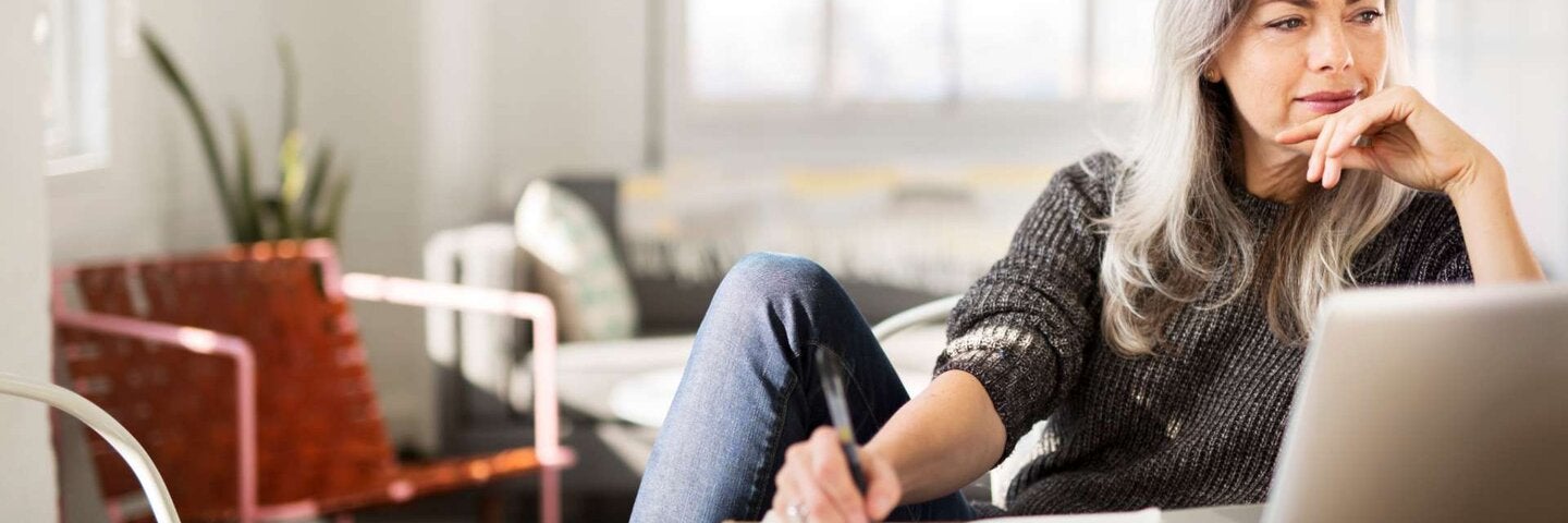 Mature woman writing while working at home