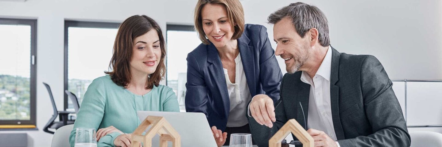 Two Realtors and an intern having a meeting in office with laptop and architectural models