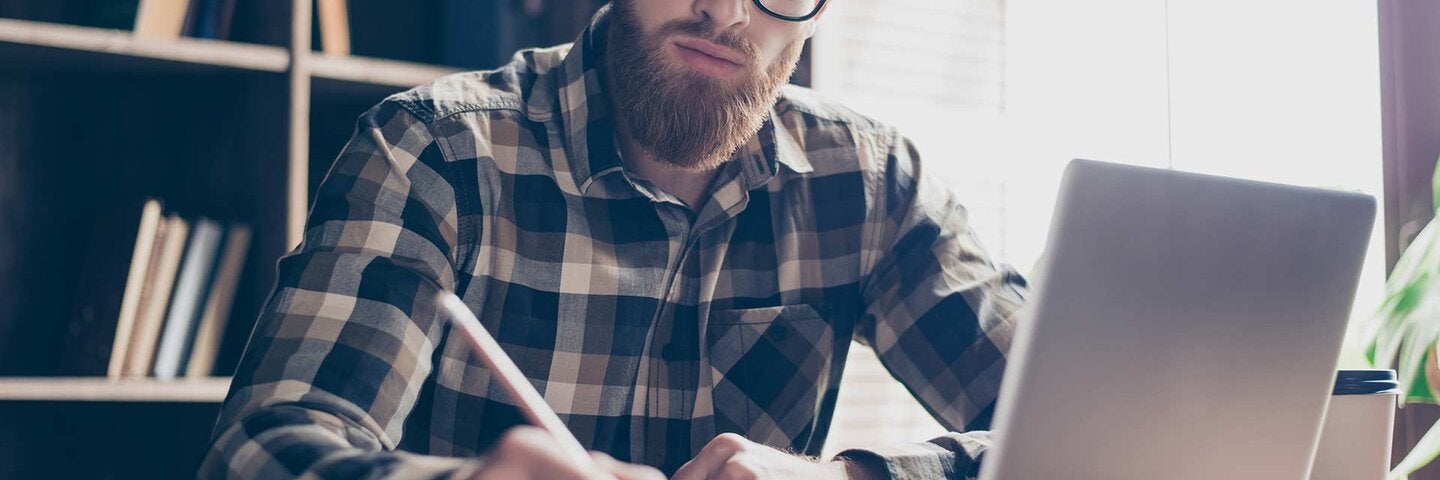 man with laptop and notebook writing
