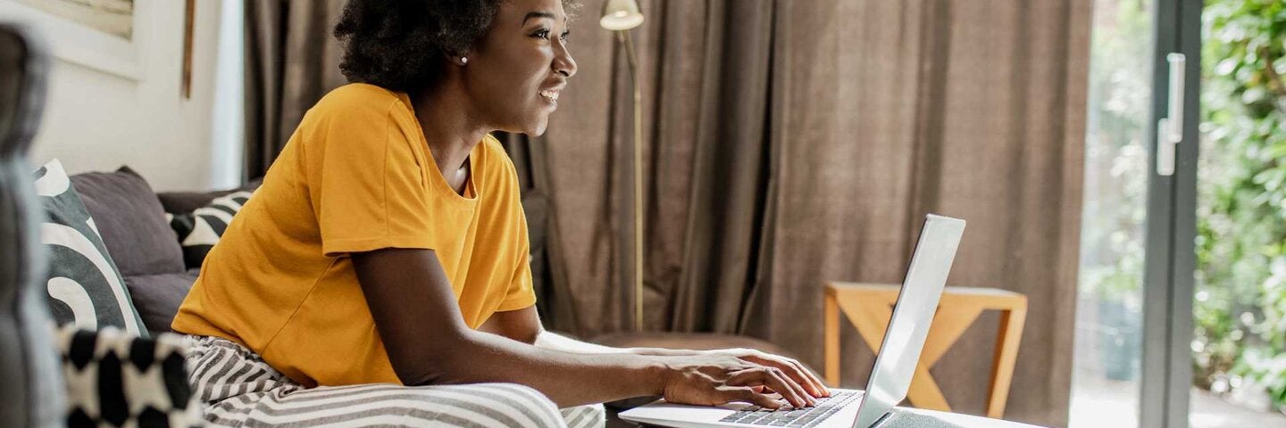 A young African American woman uses a laptop in her modern apartment