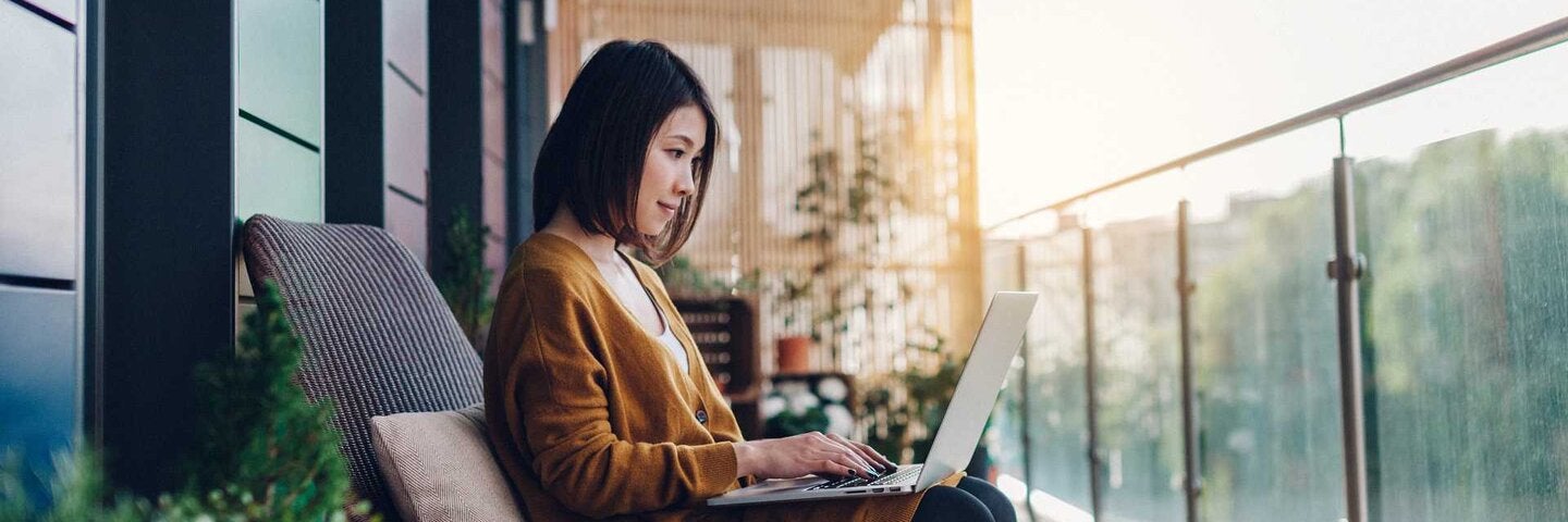 young woman workng on a laptop on a balcony