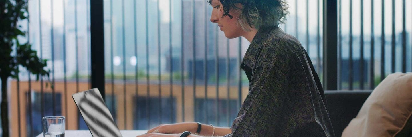 writer sitting at a desk writing on a laptop