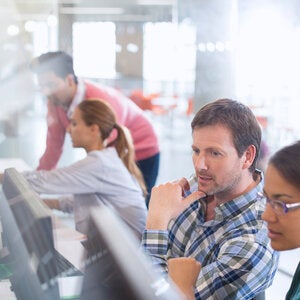 four people seated at computer desks